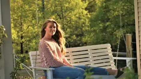 Woman swinging on a front porch swing.