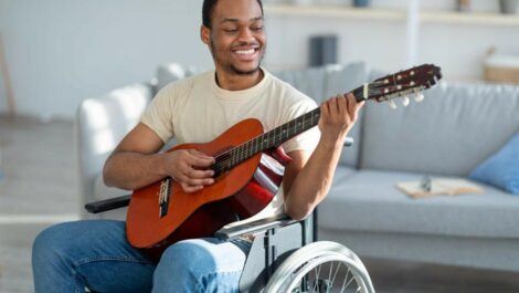 A man playing an acoustic guitar in a wheelchair