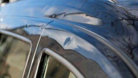 Close-up of a car roof with many hail damage dents.